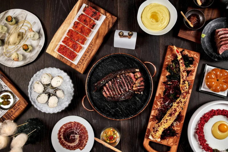 A beautifully presented spread of Bazaar Meat's signature dishes, including premium steaks.