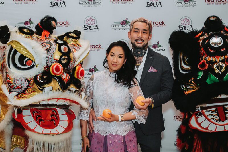 Penny Chutima and Kenny Okada offering oranges to the lion and dragon